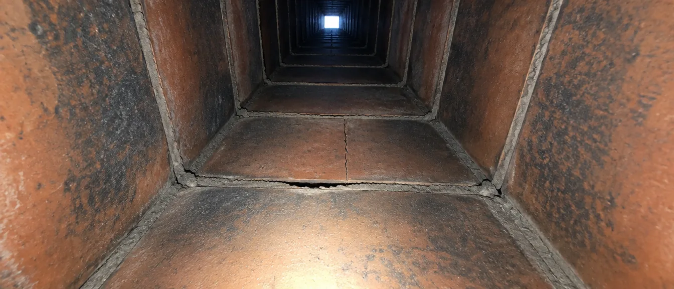 View up a clay tile flue lit by an inspection light